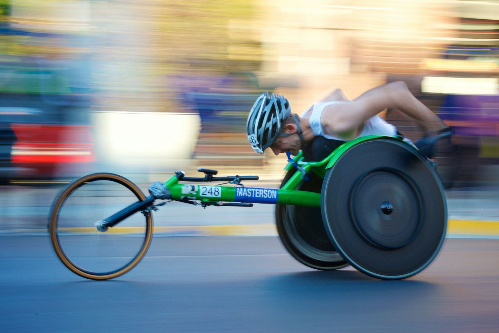 Atleta en silla de ruedas de carreras avanzando a toda velocidad durante un maratón urbano