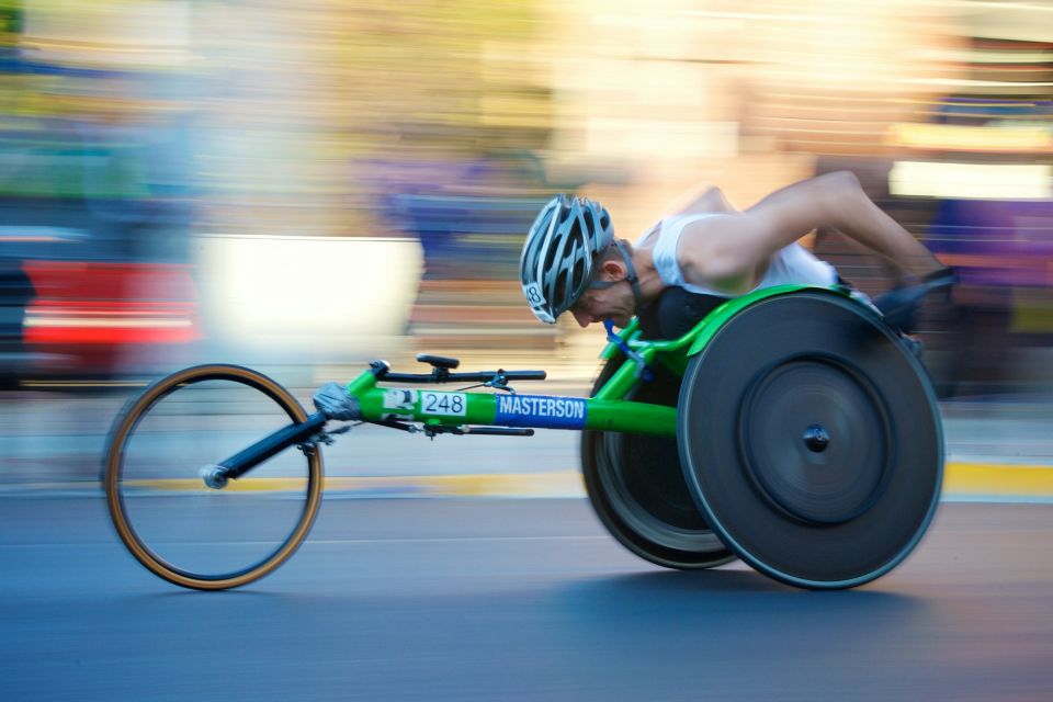Atleta en silla de ruedas de carreras avanzando a toda velocidad durante un maratón urbano