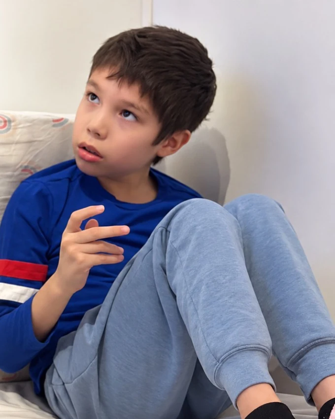 Max, con camiseta azul, sentado y mirando hacia arriba.